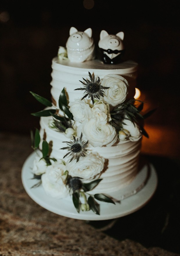 Wedding cake with pig toppers and white floral decor