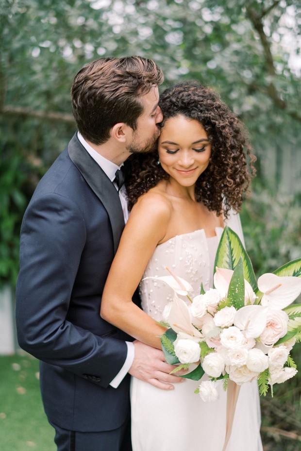 Loving groom kisses bride forehead at their wedding