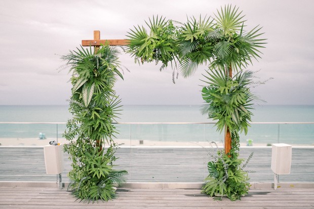 Tropical greenery wedding arch with ocean view background