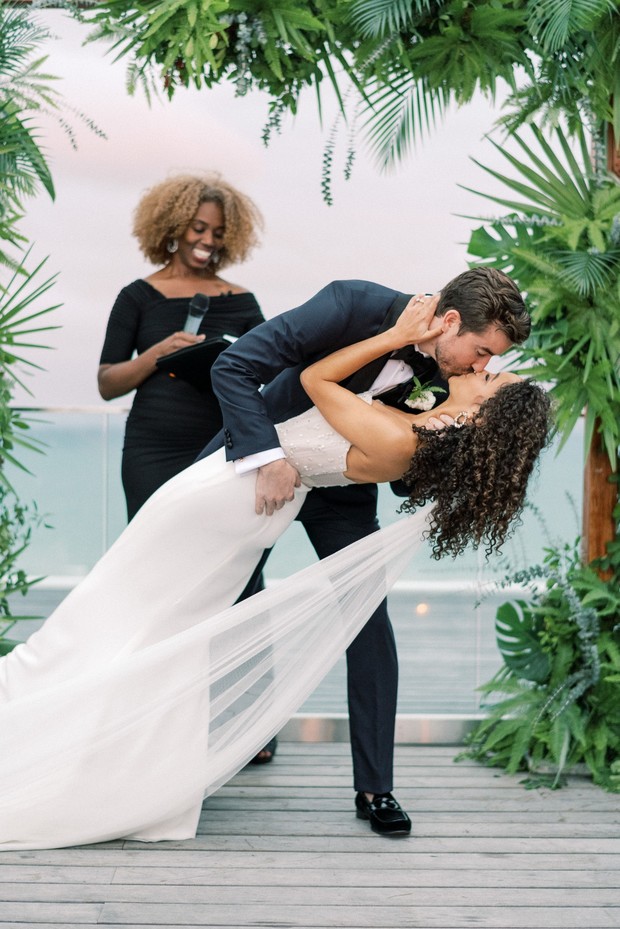 Bride and groom share a passionate kiss at their tropical wedding ceremony