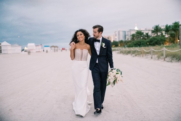 Happy couple walking on a beach after wedding ceremony