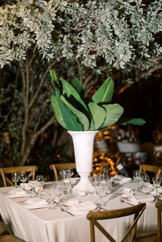 Elegant wedding table setting with tropical foliage centerpiece