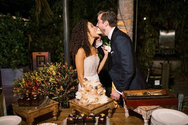 Newlyweds share a donut at their outdoor wedding reception