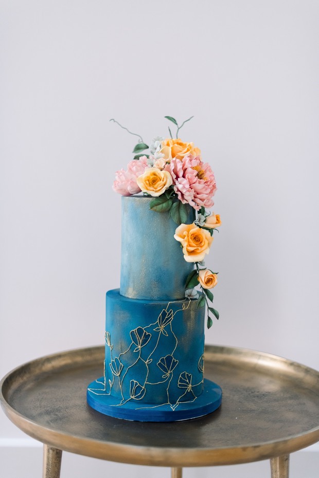 blue and gold wedding cake with florals