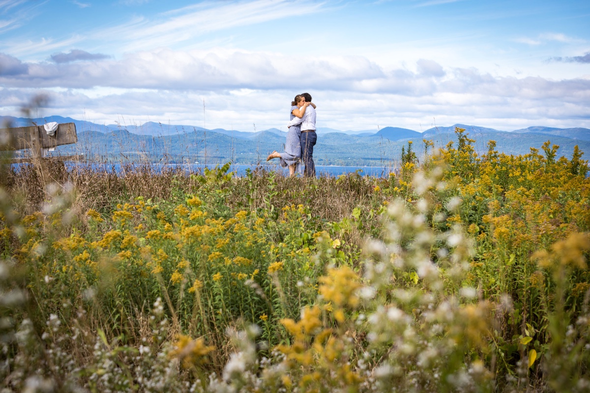 Couple hugging on a hill overlooking a lake, scenic nature view
