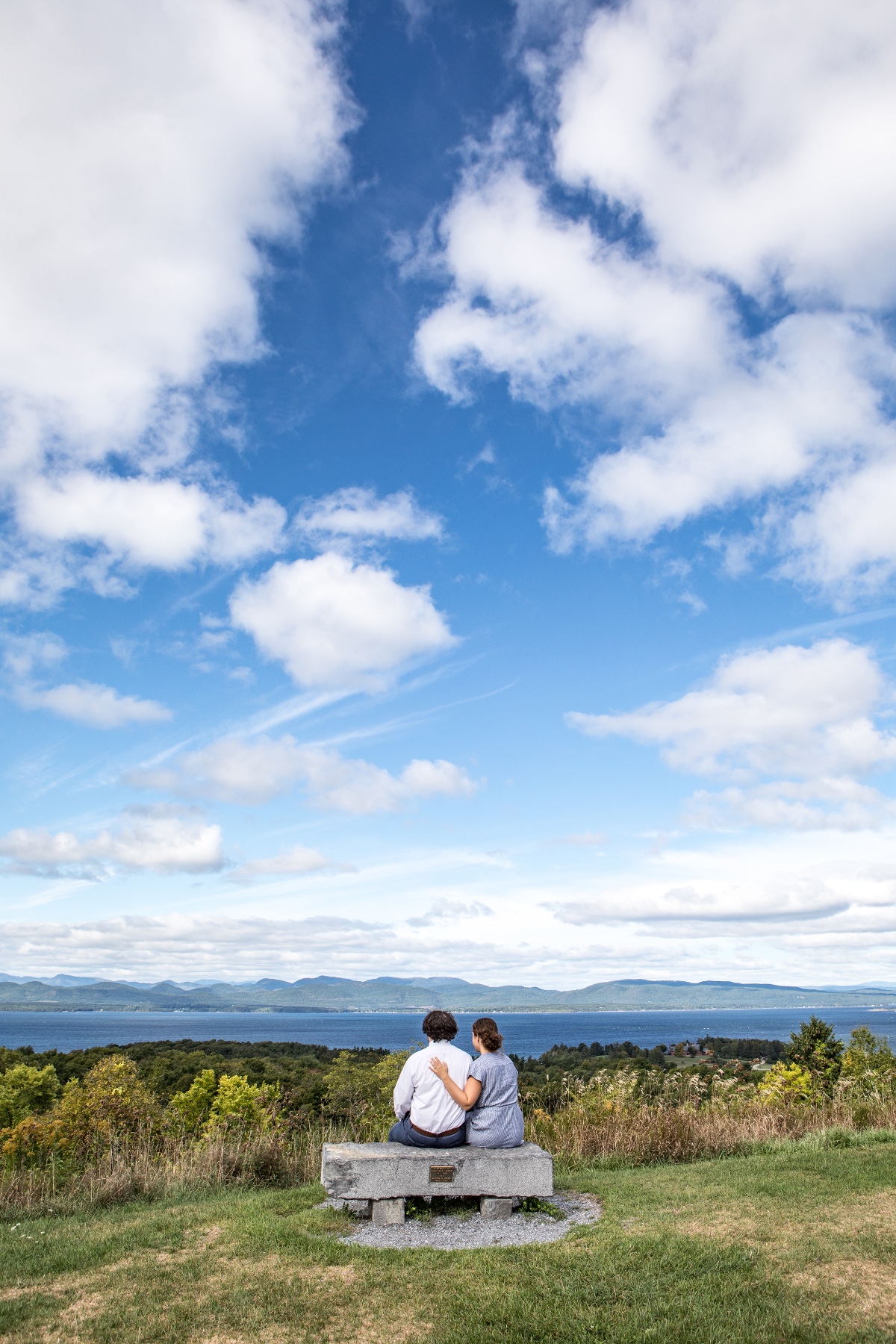 Couple enjoying scenic view on a bench under blue sky