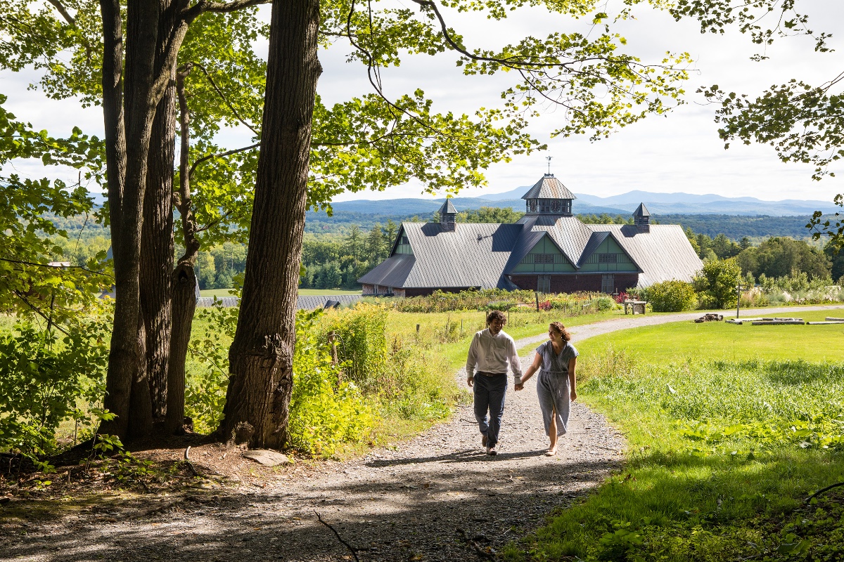 Couple walking hand-in-hand towards a barn on a sunny day