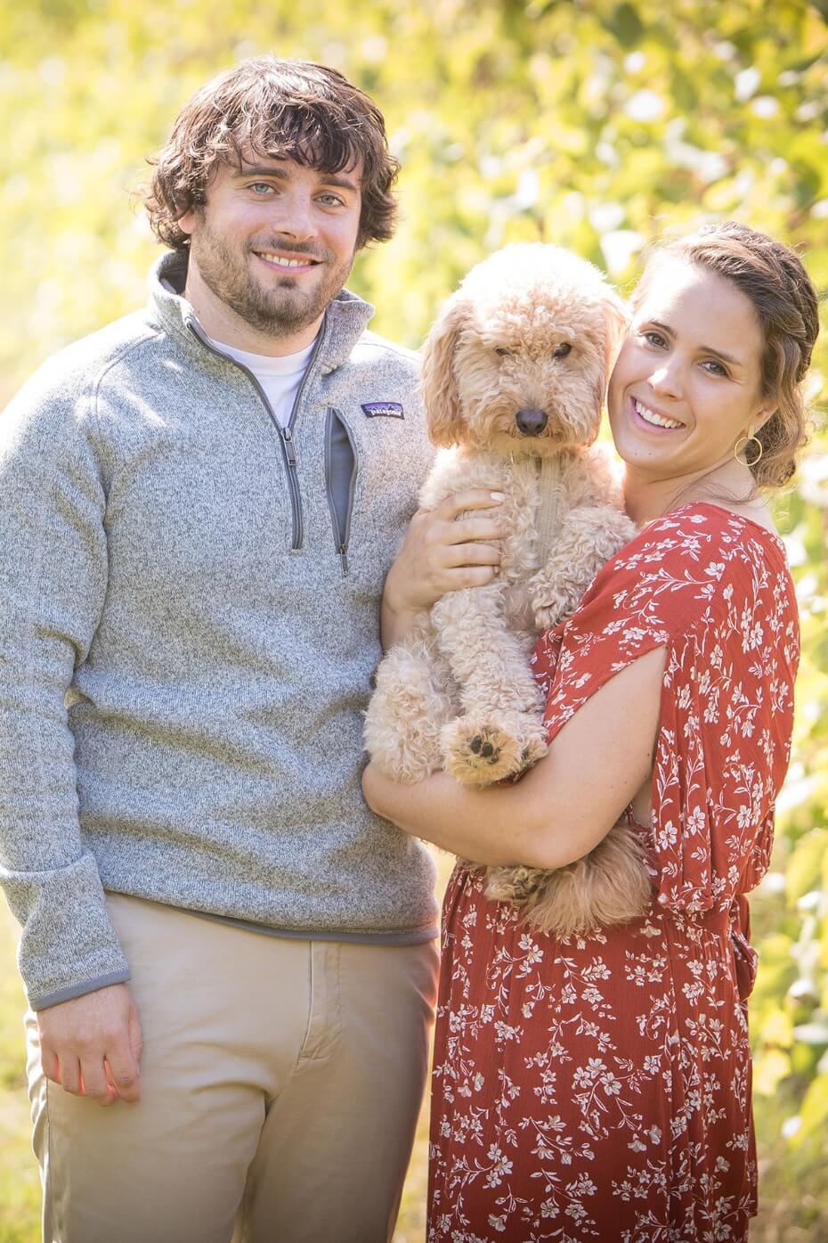 Smiling couple with their fluffy dog in a sunny outdoor portrait