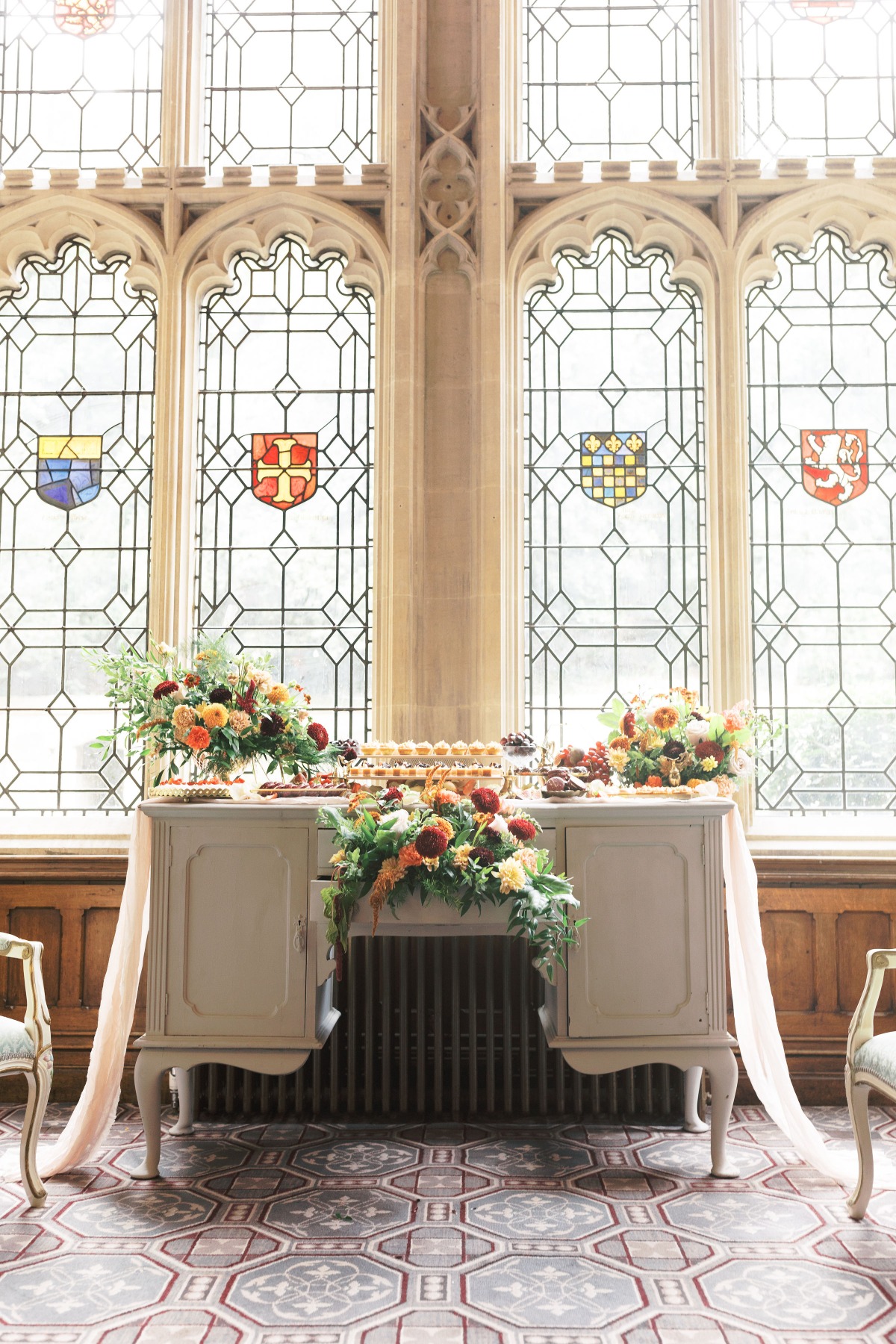 Elegant dessert table set against stained glass windows
