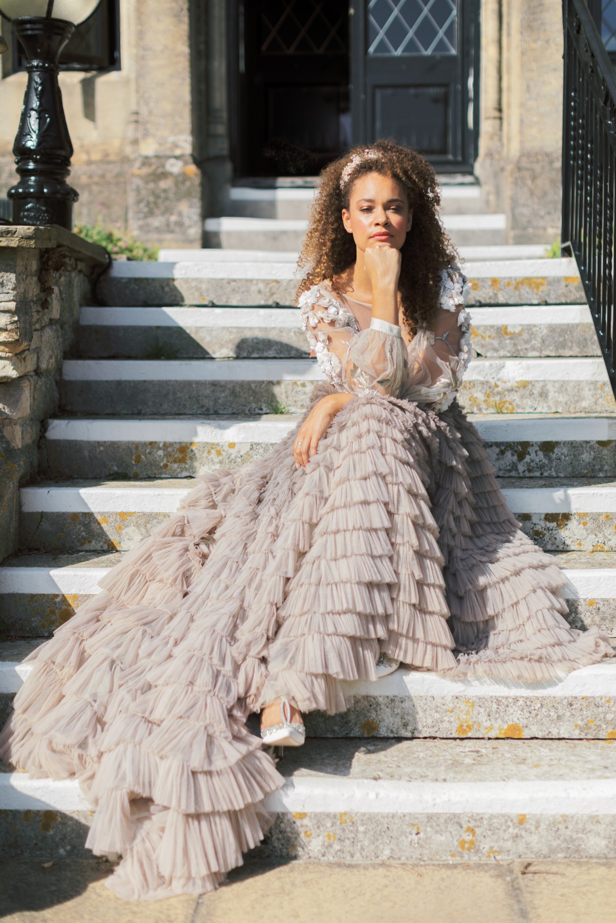 Woman in layered gown sitting on stone steps outdoors
