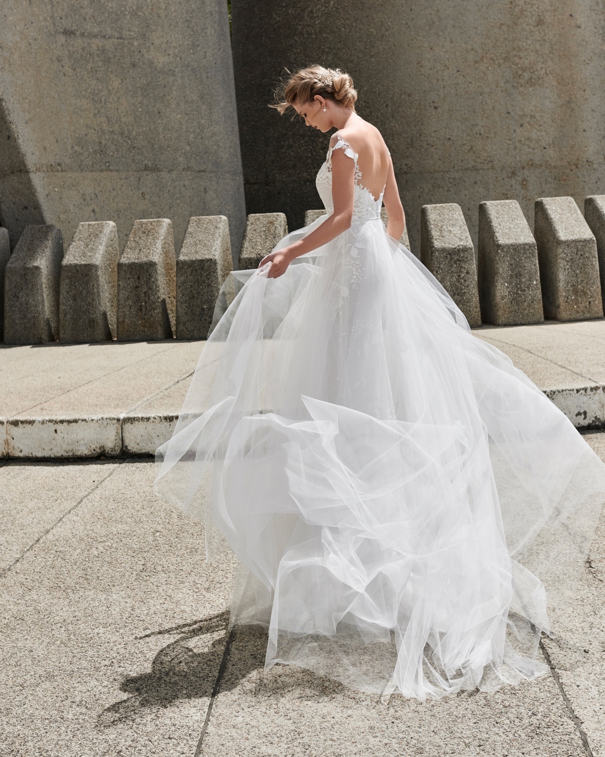 Bride in flowing wedding gown outside modern building