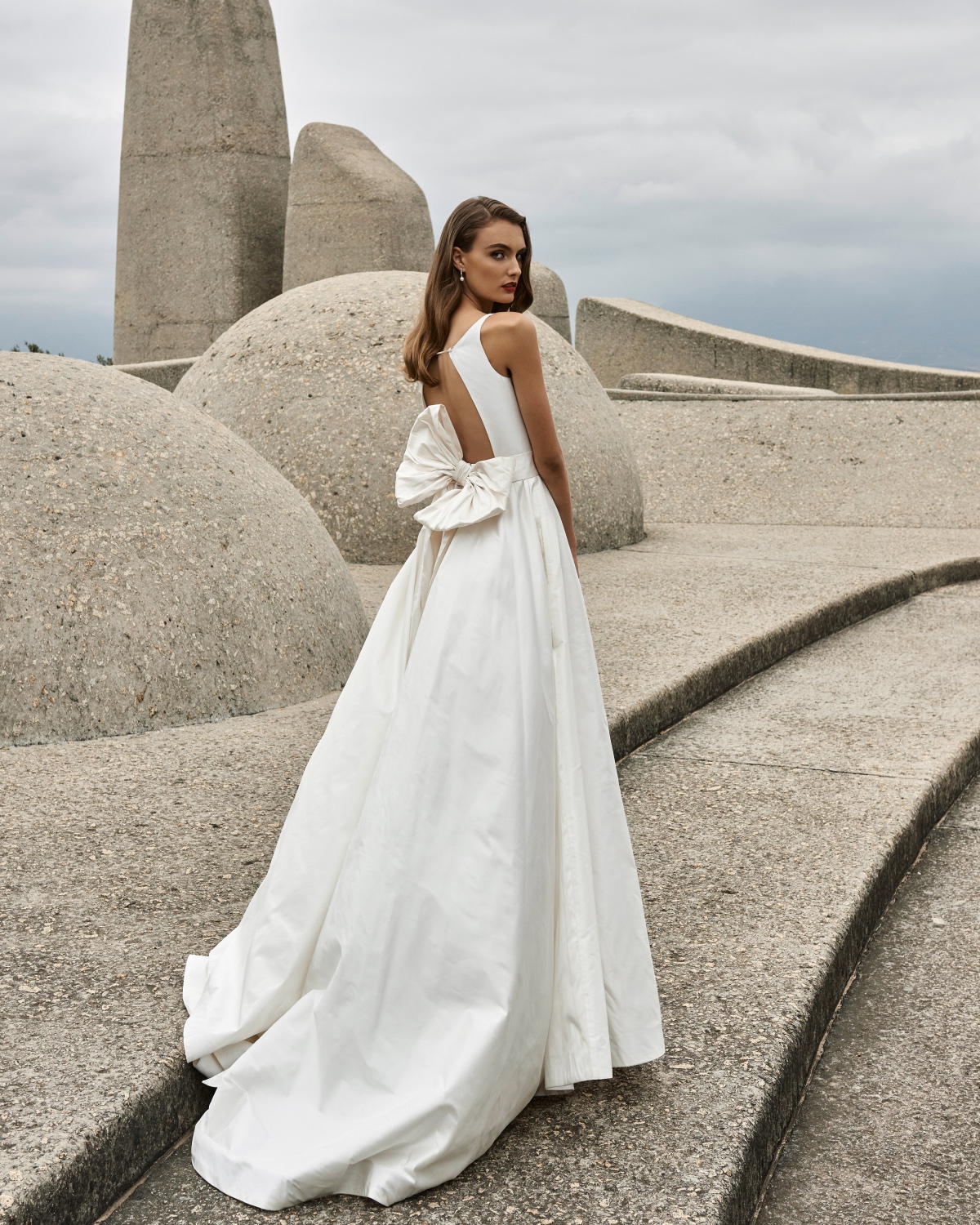 Woman in white gown with bow looking over shoulder