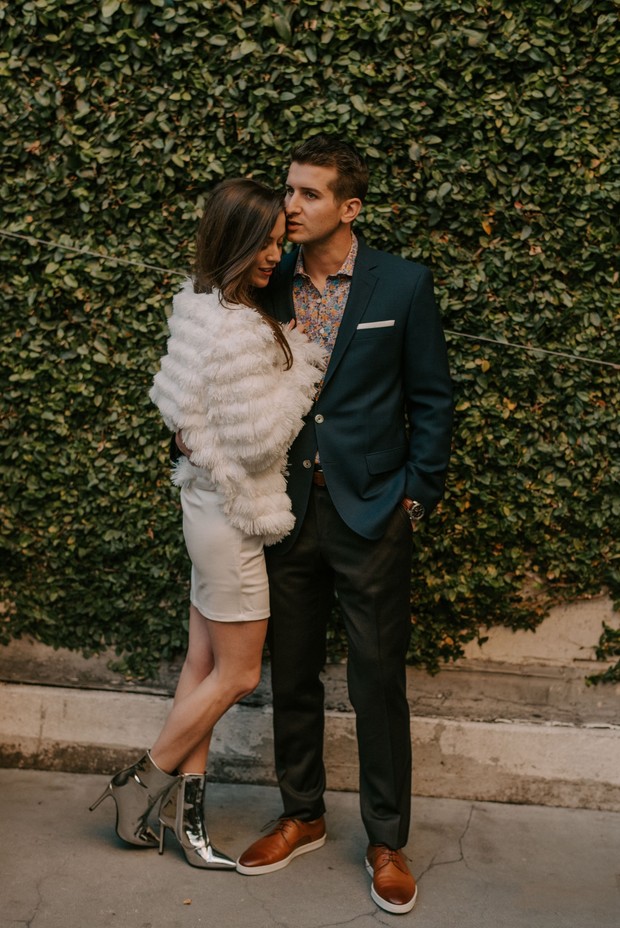 Couple posing in front of a green wall for engagement shoot