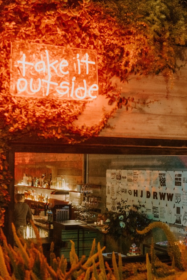 Cozy outdoor bar with glowing neon sign Take It Outside