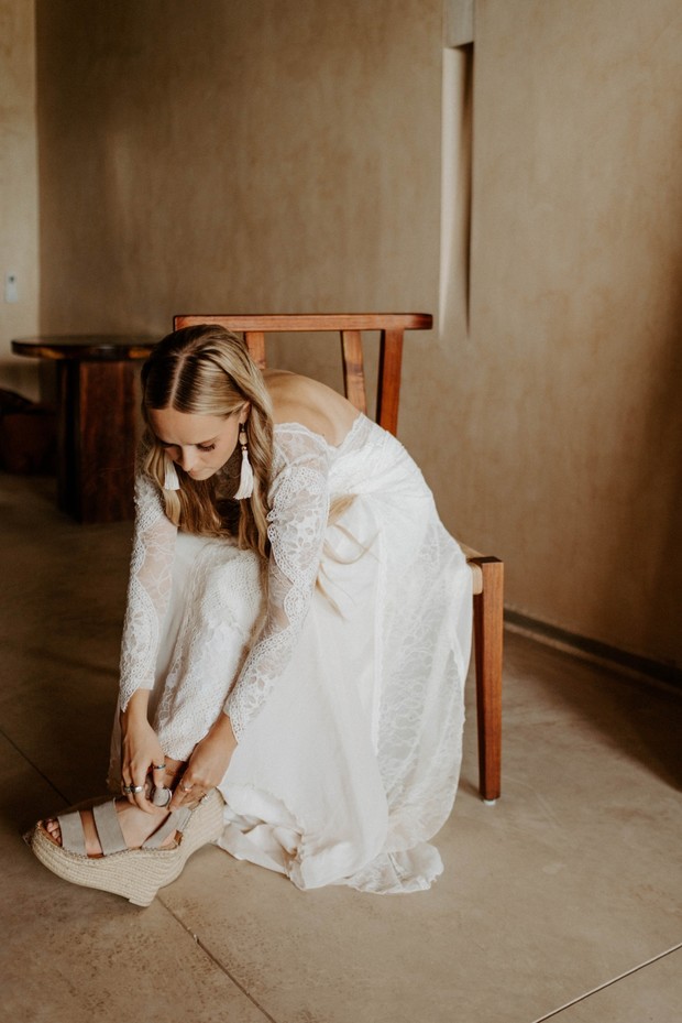 Bride fastens her wedding shoes while sitting down