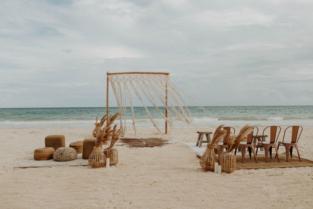 Boho beach wedding setup with macrame arch and seating