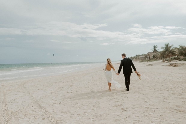 Bride and groom walk on beach after wedding ceremony
