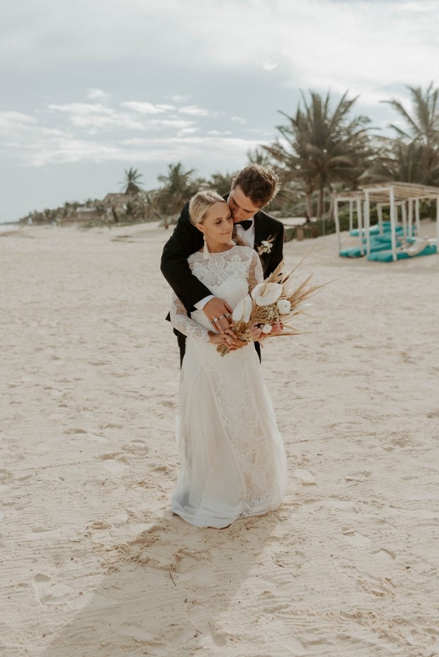 Bride and groom embrace on a sunny beach wedding day