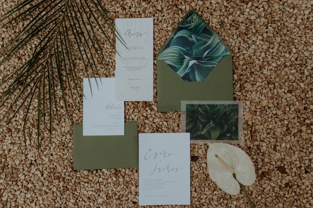 Green wedding invitation suite on pebbled background