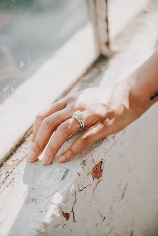 Hand resting with engagement ring, sunlit, near window