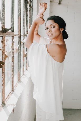Beautiful woman in white dress near a window, looking at the camera