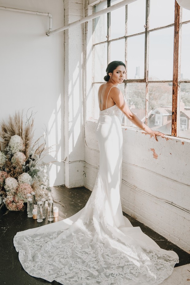 Elegant bride in a wedding dress stands by the window, looking outside