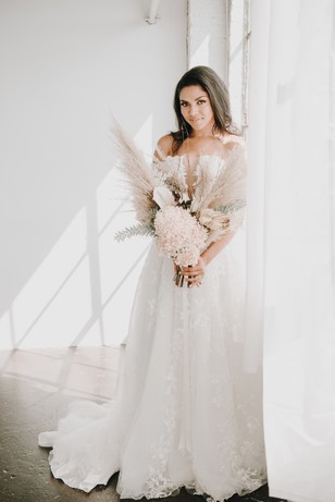 Beautiful bride in a flowing wedding dress holding flowers