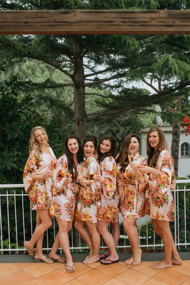 Bridesmaids in floral robes toasting with champagne