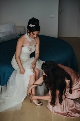 Bride getting shoes done by bridesmaid on wedding day