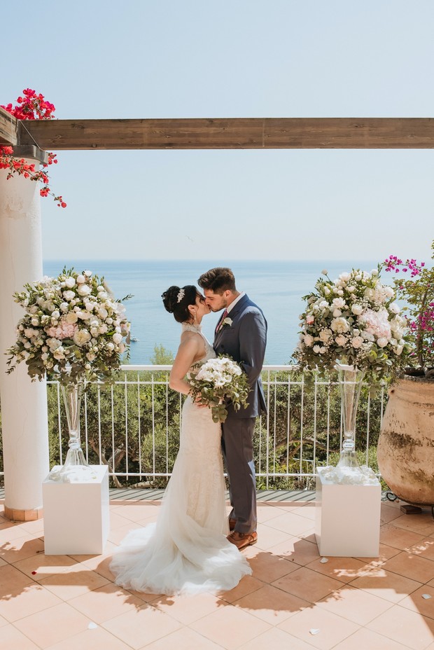 Bride and groom kiss at ocean view wedding ceremony
