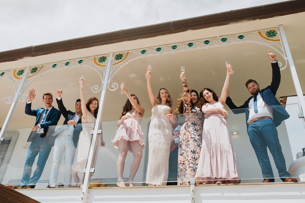 Wedding party celebrating on a balcony with champagne cheers