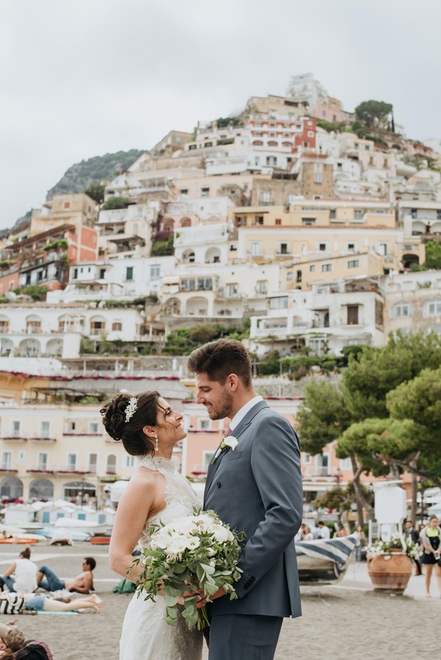 Smiling couple on their wedding day in front of coastal Italian village