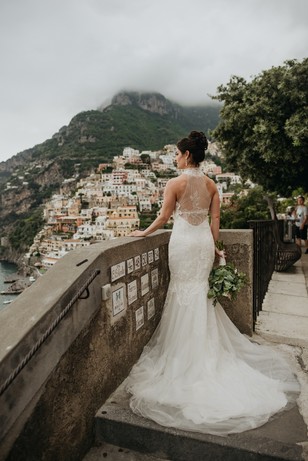 Bride in wedding dress overlooking coastal town scenery