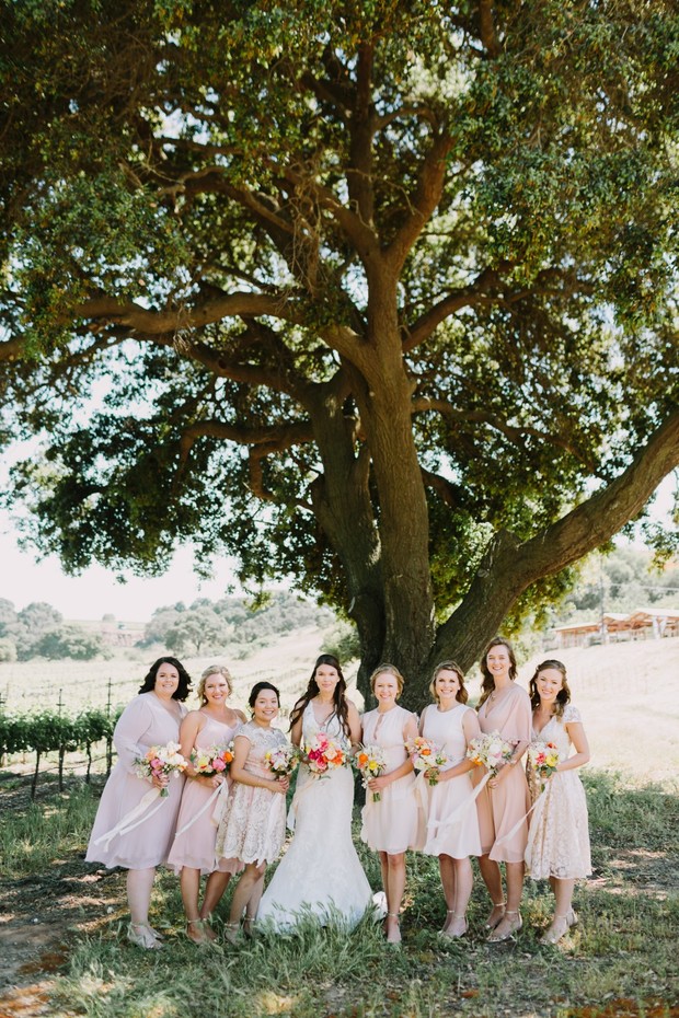 Bride with bridesmaids in blush dresses under oak tree