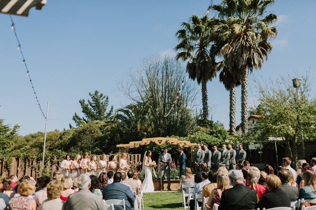 Outdoor wedding ceremony with palm trees and guests