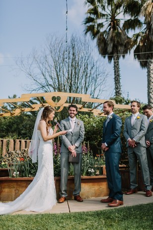 Bride reading vows at sunny outdoor wedding ceremony
