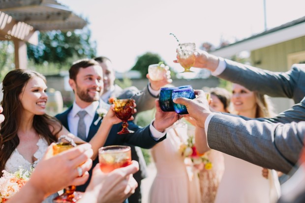 Wedding guests cheer with drinks at outdoor reception