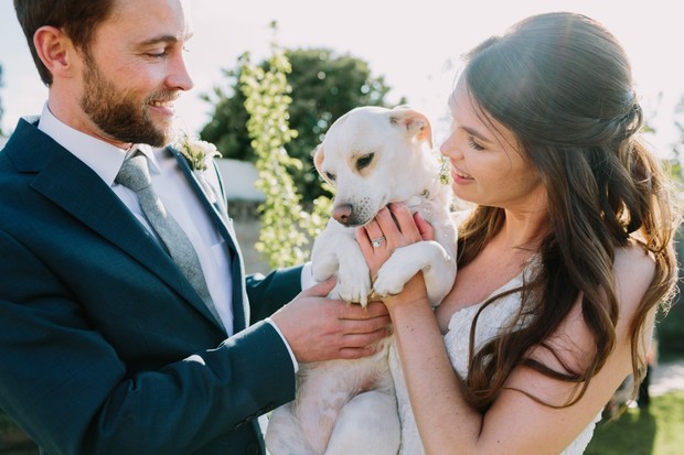 Bride and groom lovingly hold their dog at their wedding