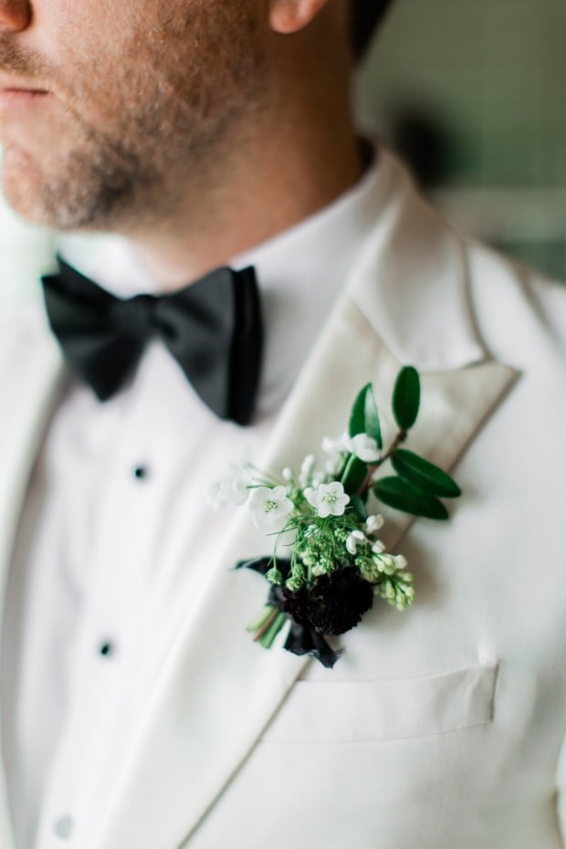 groom in white suit jacket with black and white boutonniere