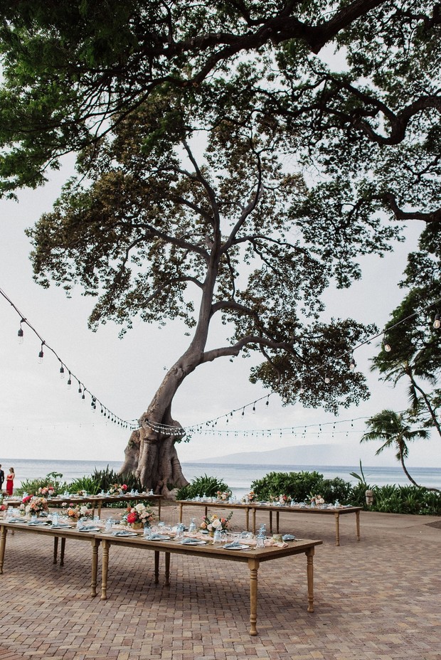 Outdoor wedding reception under a large tree by the ocean
