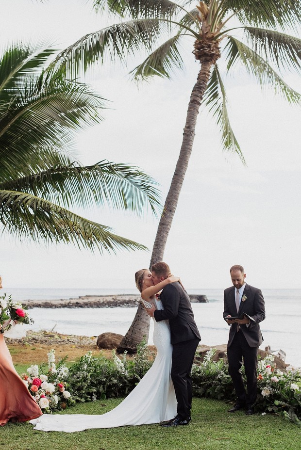 Bride and groom share first kiss at tropical beach wedding