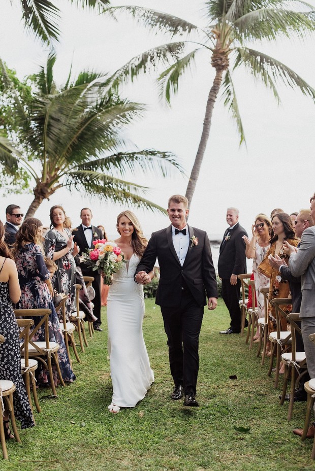 Newlyweds walk down aisle at tropical outdoor wedding