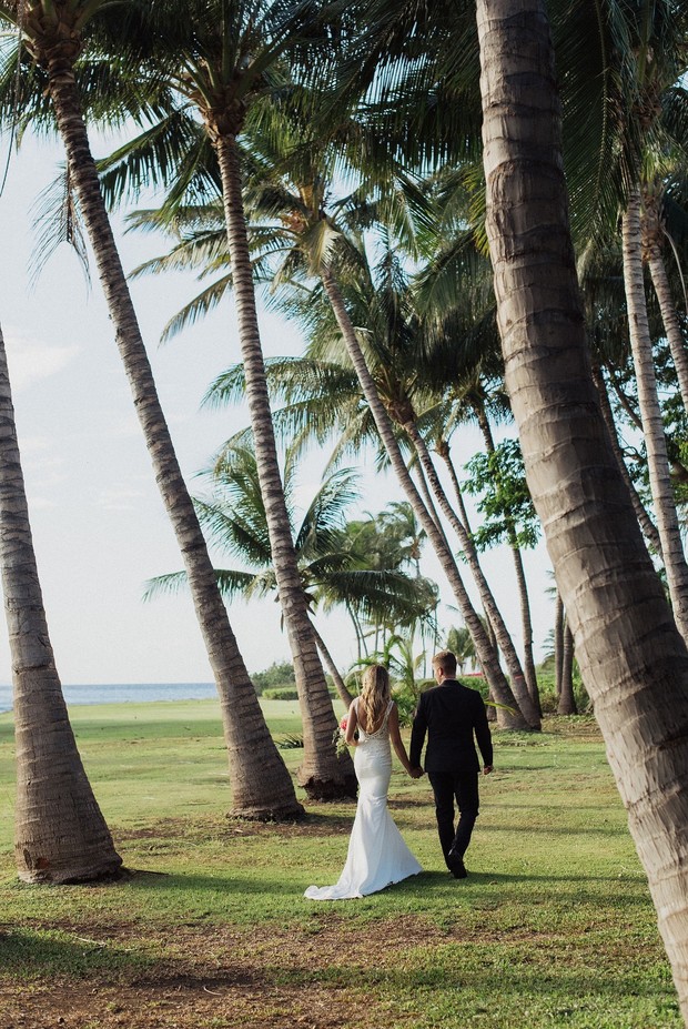 Bride and groom walk among palm trees at tropical wedding