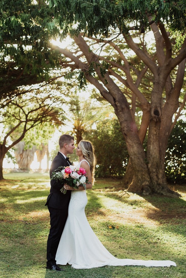 Bride and groom embrace in a sunlit outdoor wedding