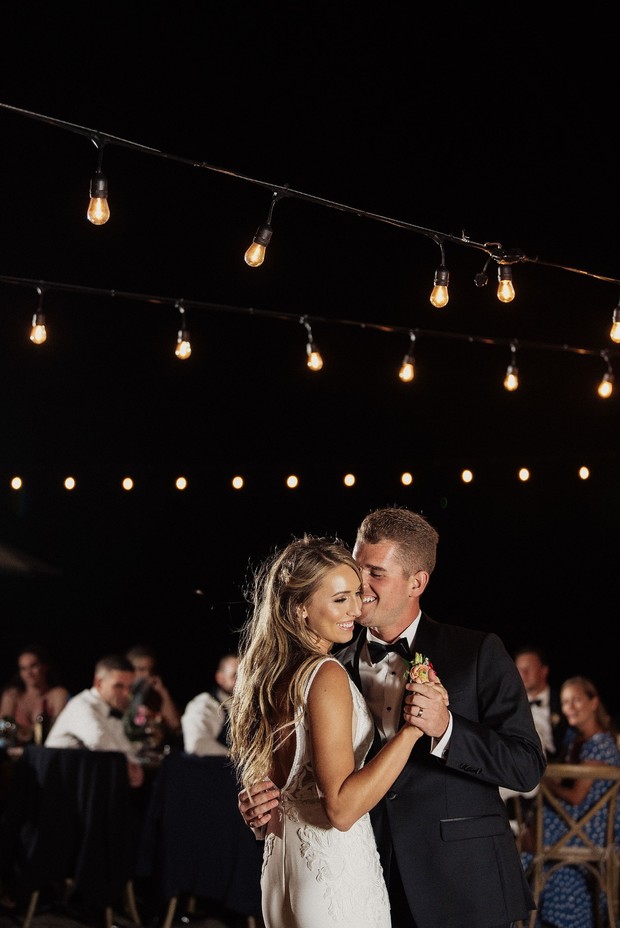 Bride and groom first dance under string lights