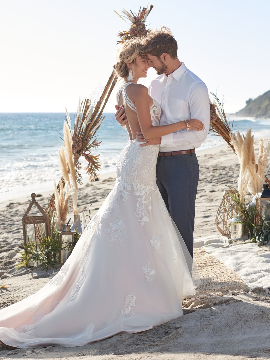 Romantic beach wedding of a couple embracing tenderly in a gown
