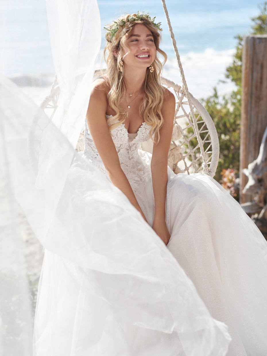 Beautiful bride in a white dress smiles, enjoying her special day by the beach