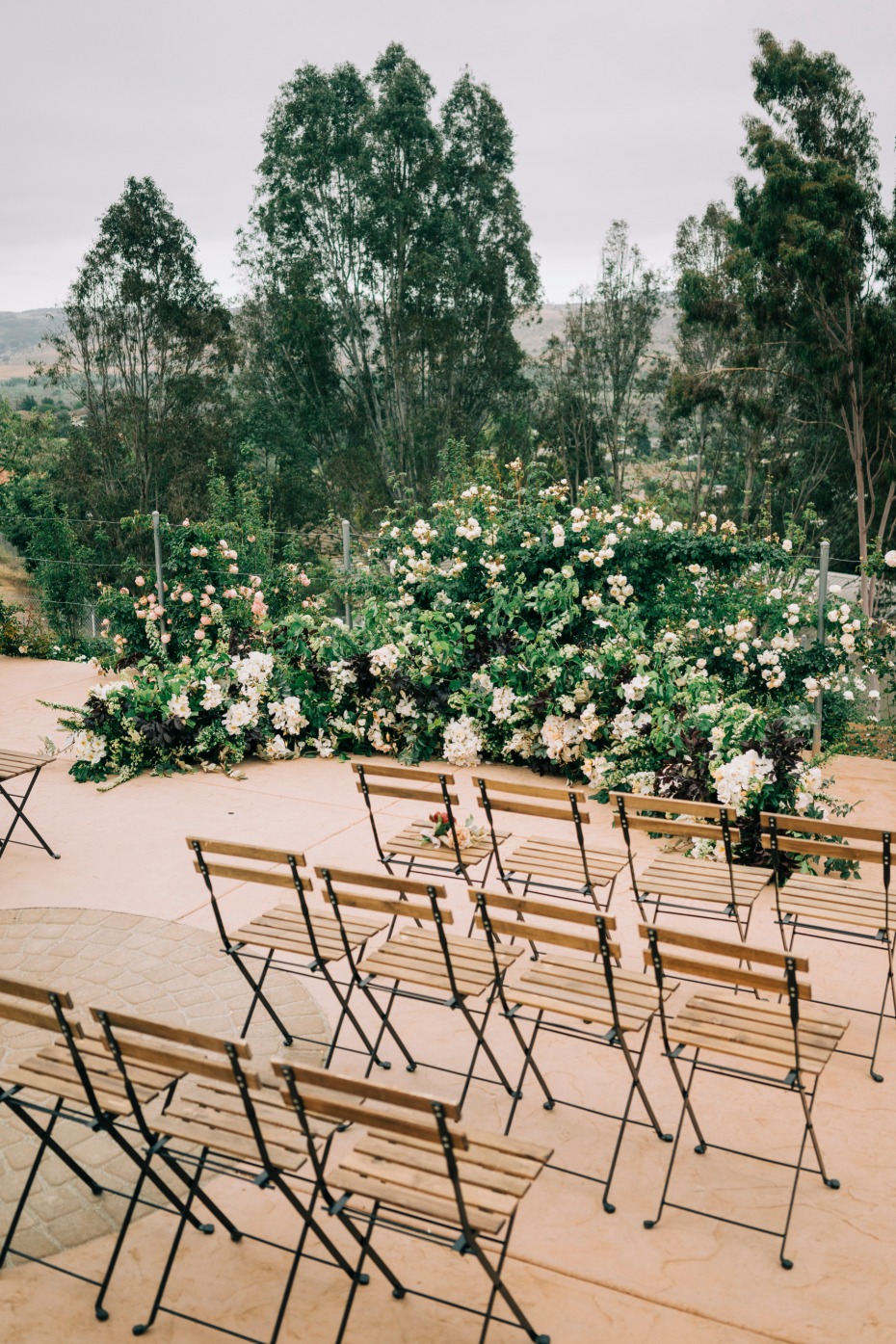Outdoor wedding venue with wooden chairs and flowers