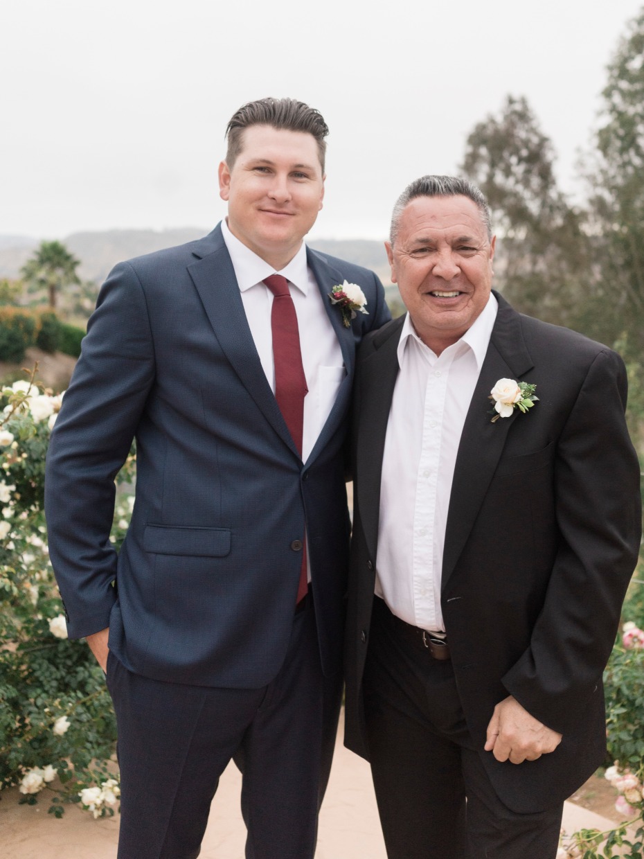 Two men in suits pose for a wedding day photo together