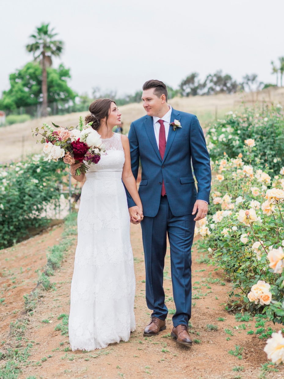 Bride and groom walking in a rose garden on their wedding day